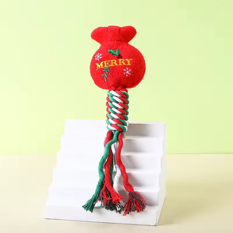 Durable Christmas dog rope toy featuring a red plush sack top embroidered with 'MERRY' and a braided red, green, and white cotton rope handle.