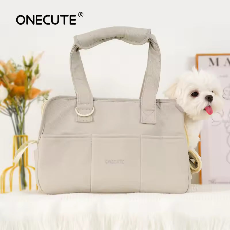 Hand carrying the beige portable dog carrier handbag with a small white dog resting comfortably inside.