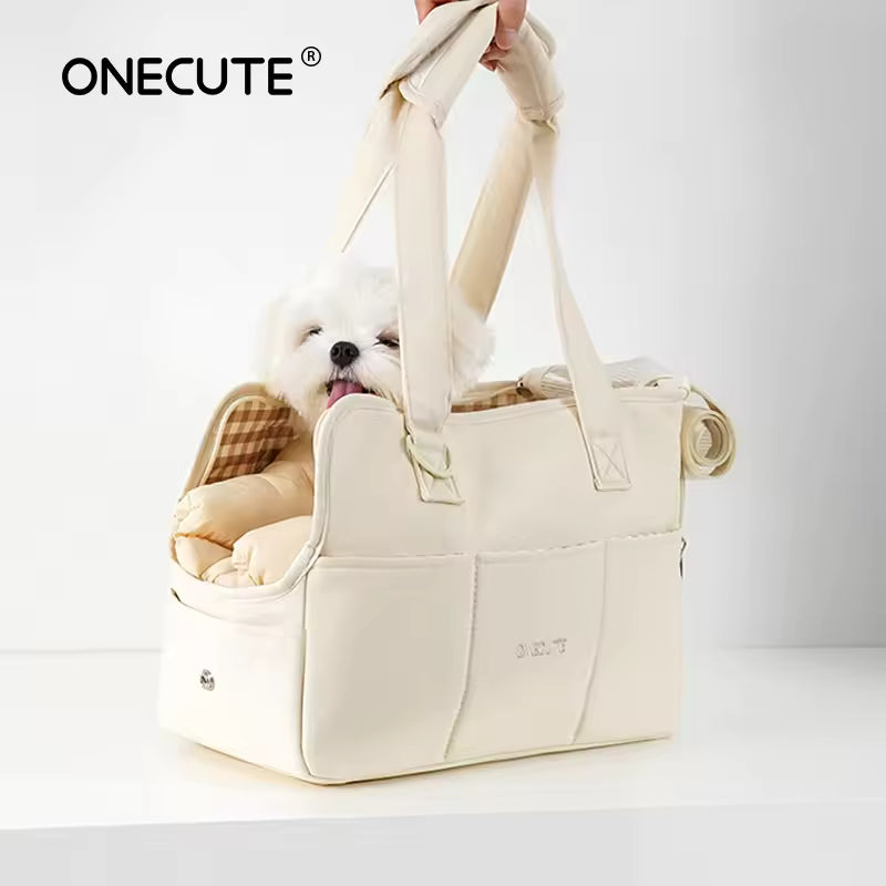 Hand carrying the beige portable dog carrier handbag with a small white dog resting comfortably inside.