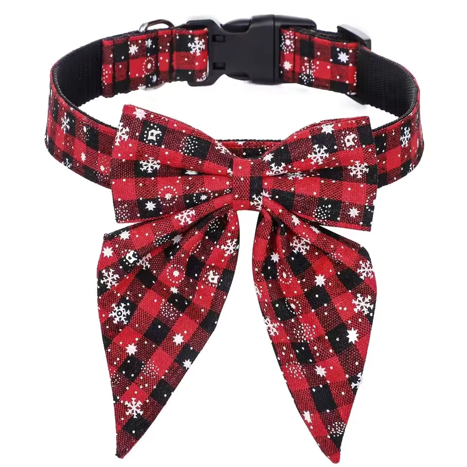 Close-up of an adjustable pet collar with a large detachable bow tie in a red, white, and green plaid pattern with white snowflake print.

