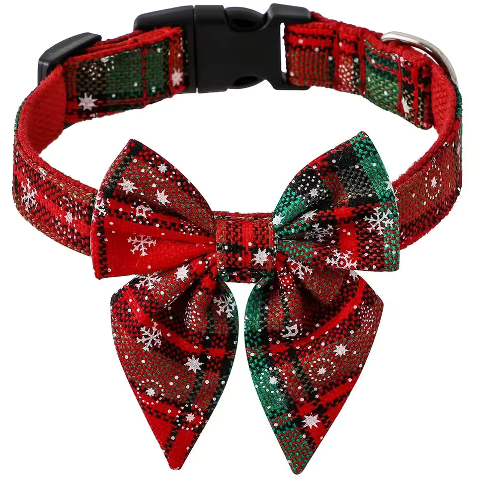 Close-up of an adjustable pet collar with a large detachable bow tie in a red and green plaid pattern with white snowflakes.